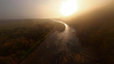 FPV uçuşu muhteşem yaz nehri, sonsuz yaz çayırları ve dağ ormanları üzerinde. Gün doğumu gökyüzü. Güneşli bir sabah. Görkemli hava görüntüsü.