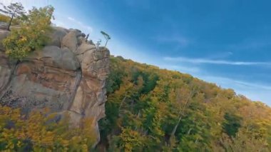 Dovbush Kayaları. Olağanüstü doğa vahşi orman ve dağlık alan. Havadan FPV manzarası. Genç, erkek, aşırı gezgin kayaların üzerinde atlıyor. Yürüyüş kavramı.