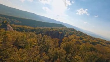 Güzel ormanları olan dağlık alanın insansız hava aracı görüntüleri. Dovbush Kayaları. Meşhur Ukrayna istikameti. Erkek turist yürüyüş yapmaktan zevk alıyor. Tırmanırken kollarını kaldırıyor..