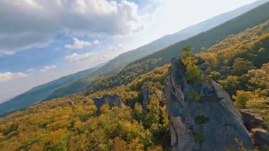 Açık doğada FPV çarpıcı bir uçuş, güzel renkli orman ağaçları ve pürüzsüz kayaların üzerinde uçuyor. Uçurumun tepesindeki maceraperest gezgin. Orman. Peyzaj.