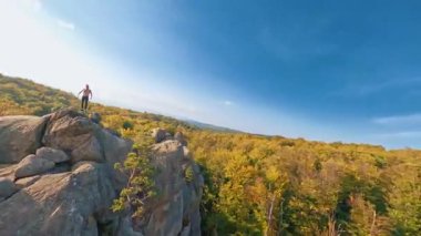 Carpathian dağlarında fantastik bir uçuş. Dovbush kayalarından oluşan muhteşem bir manzara. Uçurumun kenarında durup özgürlüğe hayran olan mutlu bir gezgin. Seyahat güzergahı. Ukrayna.