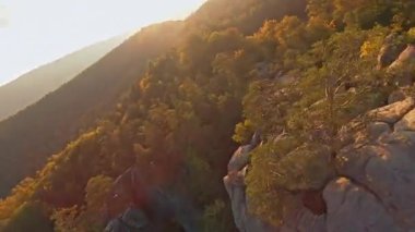 Dağlık alanda sinematik uçuş. Renkli sonbahar ağaçları arasında Dovbush 'un muhteşem kayalıkları. Orman robotu. FPV seyahat videosu.