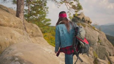 Genç aktif gezgin kadın çekici sırt çantalı turist kayalıklara tırmanıyor ve manzaranın tadını çıkarıyor. Doğa çevresi. Özgürlük gezisi. Yürüyüş yolu.