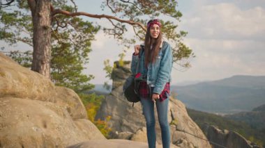Şaşırtıcı genç beyaz kadın maceraperest gezgin turist sırt çantasıyla uçurumun tepesinde durmuş gülümseyerek doğal yaz tatilinin tadını çıkarıyor. Portre. Dağlar. Manzara.
