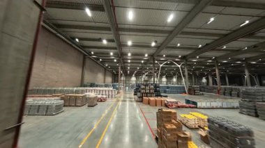 Lojistik depo FPV görüntüsü. Perakende sanayi deposunda hava aracı uçuşu. Teslimat malları ve personel işçileriyle dolu..