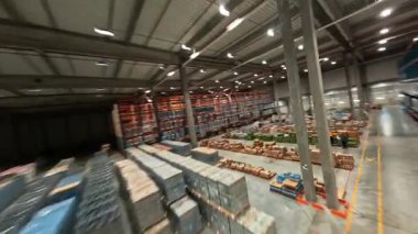 Depoda FPV hava uçuşu. Teslimat malları olan büyük bir sanayi deposu. Lojistik konsept. Hız dronu görünümü.