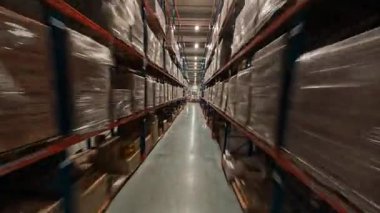 Deponun içinde hızlandırılmış görüntü. Raflar arasında teslimat mallarıyla FPV uçuşu. Endüstriyel raflarda bir sürü karton kutu var. Lojistik Merkezi.