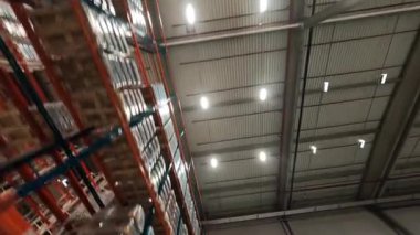 FPV insansız hava aracı görüntüsü modern endüstriyel perakende satış deposunda. Karton kutularla dolu raflar. Lojistik Merkezi Deposu.