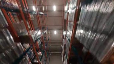 Modern büyük deponun içinde manevra kabiliyeti olan FPV uçuşu. Büyük lojistik merkezi ürün dağıtım deposuna bak. Mallı raflar.