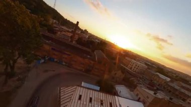 Gün batımında ilham verici şehir manzarasında havadan FPV uçuşu. İnşaat alanları, tarihi evler ve pitoresk caddeler. Drone görünümü.