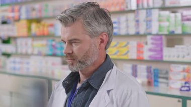 Beyaz takım elbise giyip eczanede çalışan yakışıklı, yetişkin beyaz erkek eczacının portresi. Eczacı. Eczane.