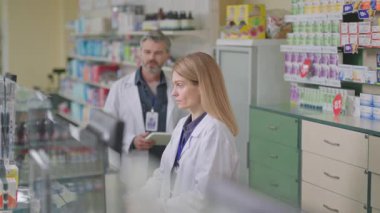 Erkek eczacı doktor ve kadın danışman bilgisayarla konuşuyor. Birlikte eczanede çalışan viral tedavinin tıbbını tartışıyorlar. Modern eczane.