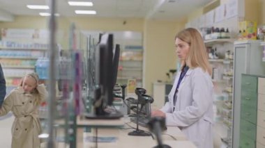 Baba ve kızı eczaneye geliyor, kadın eczacı doktorla görüşüyor, tavsiye ve ilaç alıyorlar. Eczacı dükkanı. - Aile. Danışma.