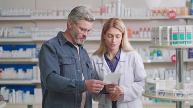 Beyaz, yetişkin, yakışıklı bir adam kadın eczacıyla görüşüyor. Eczacı kadın çalışan müşterilere sağlık ürünleri öneriyor. İlaç satıyorum..