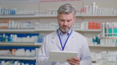 Tıbbi elbise giyen, bilgisayar tableti kullanan, ilaç kullanan ve müşteri için reçete yazan profesyonel bir Kafkasyalı doktor. Sağlık görevlileri. Eczane.