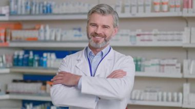 Yakından gülümseyen yakışıklı eczane danışmanı yetişkin beyaz erkek doktor işçi kıyafeti giyiyor ve eczanede gururla çalışıyor. Eczacı..