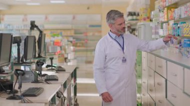 Gri saçlı olgun doktor eczacı hasta kadın müşterilere ilaç paketi öneriyor. Anne ve kızı. Hasta danışmanlığı. Eczacı..