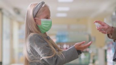 Lviv, Ukrayna - 19 Mayıs 2021 - Genç anne kızı için eczaneye antiseptik sprey kullanıyor. Dezenfekte sıvısıyla ellerini ovuşturan sevimli bir kız çocuğu. Salgın sırasında sağlık hizmetleri.