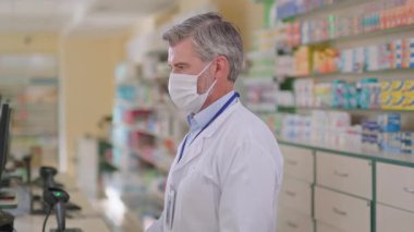 Kimya alanında çalışan profesyonel bir yetişkin eczacı kameraya poz veren maske giyen bir bilgisayar kullanıyor. Eczane. Modern eczane. Eczacı..