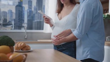 Müstakbel bir çift hamile eş ve koca çocuk bekliyor. Modern şık ev mutfağında ultrason ekografi fotoğrafı izliyorlar..
