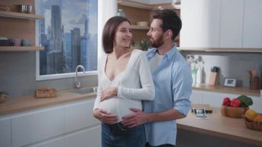 Genç ve güzel bir karısı olan koca mutfakta el ele tutuşuyor. Aile hayatı. Çift portresi. Sevecen müstakbel ebeveynler.