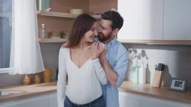 Aile anları. Ebeveynler. Hamile, genç ve mutlu bir kadın. Yakışıklı kocası gülümsüyor. Bebeğin mutfakta birlikte yemek yapmasını bekliyor..