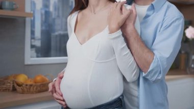 Aile amaçları. Müstakbel güzel anne babalar, bebeğin el ele tutuşup mutfakta kucaklaşmasını bekliyorlar. Rahat bir ev. İç mekanlar. İlişki.