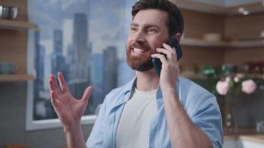 Bir adam modern ve şık bir mutfakta telefonuyla konuşurken, çağdaş iç tasarımı sergiliyor.