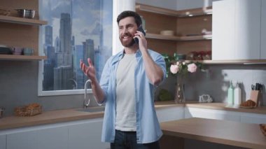 Bir adam modern ve şık bir mutfakta telefonuyla konuşurken, çağdaş iç tasarımı sergiliyor.