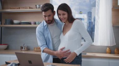 Çok mutlu bir çift, şık bir mutfak ortamında eğlenirken internetten neşe içinde etkileşim kuruyor.