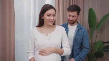 Evinde kocası olan evli bir çift. Neşeli sakallı adam oturma odasında karısına sarılıyor. Daire. Aile hayatı.