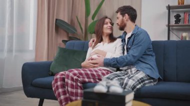 Aile hayatı anları. Mutlu bir koca, hamile bir eş koltukta oturuyor, gelecekle ilgili planlarını paylaşıyor ve birlikte eğleniyorlar. İlişki. Hamilelik.