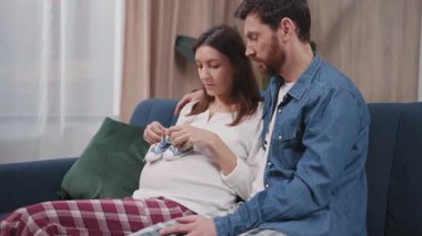 Birkaç neşeli Kafkasyalı müstakbel ebeveyn kanepede oturmuş iletişim kuruyor. Kocasıyla konuşan güzel hamile bir genç kadın. Hamilelik. Aileler.