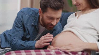 Sevecen evli bir çift bebek tekmeleri dinliyor ve sarılıyorlar. Güzel bir anne ve baba çocuk bekliyor. Destek. Aile.