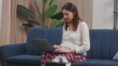 Çekici, hamile bir kadın, bebek bekliyor. Uzak bir projede çalışıyor. Oturma odasındaki bilgisayar laptopunu kullanarak iş başvurusunda bulunuyor..
