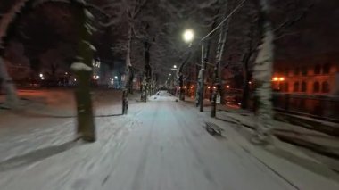 FPV 'nin insansız hava aracı, pitoresk kış akşamları şehri boyunca uçuyor. Gece lambaları aydınlanıyor. Şehir merkezinin sokakları buz ve karla kaplı. Noel tatili atmosferi.