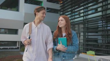 Kafkasyalı neşeli bir çift erkek sınıf arkadaşı üniversite kampüs binasının yanında ev ödevi hakkında konuşuyor. Yüksek teknoloji üniversitesi. Modern öğrenciler.