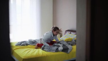 Canlı ve havadar bir yatak odasında neşeli ve neşeli bir insan neşeyle dans eder, mutluluk ve enerji saçar.