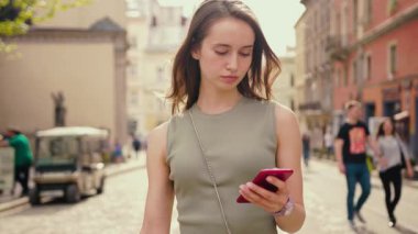 A young woman confidently navigating the bustling city streets while actively using her smartphone device