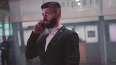 Şık ve iyi giyimli bir işadamı modern ve çağdaş bir ofiste önemli bir telefon görüşmesi yapıyor.