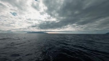 Sonsuz güzel mavi denizin ilham verici doğal görüntüsü, kalın gri bulutlar ve ufuk çizgisi. Suyla denize açılmak. Deniz aktivitesi.