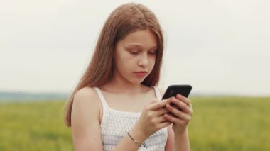 Kafkasyalı genç bir kızın akıllı telefonu elinde tutarak sohbet edişinin yakın çekim görüntüleri. Gadget, cihaz, teknoloji, gündüz. İletişim. Köy geçmişi.