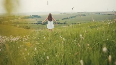 Açık yeşil alanda duran zarif beyaz elbiseli harika bir kızın arka plan görüntüleri..