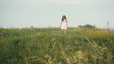 Tarlada yürüyen ve çiçek toplayan zarif bir hanımın fotoğrafı. Kadınsı bir görüntü. Kız gücü. Açık havada. Yaz zamanı. Köy.