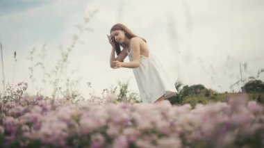 Çiçek toplayan küçük hanımın göz kamaştırıcı manzarası. Beyaz romantik elbiseli tatlı bir kız görüntüsü. Açık havada. Köy. Alan.