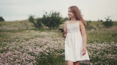 Ön cephede narin pembe çiçekler. Tarlada yürüyen büyüleyici küçük bir kız resmi. Dışarı çıkın. Köy. Yaz zamanı. Güneşli bir gün. Görüntü.