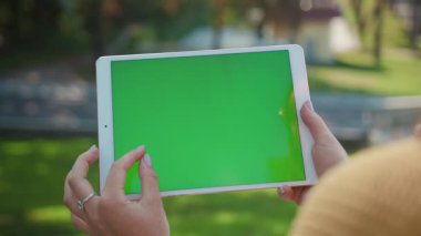 Elinde tabletle gezen genç bir kadın yeşil ekran sahte krom anahtar ekranında hareketler yapıyor. Yakın plan..