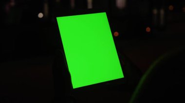 Modern girl using digital tablet computer with interactive greenscreen chrome key display mock-up technology at night. Close-up.