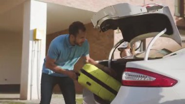 Bagaja bavul yükleyen yakışıklı genç adamın yakın çekimi. Mutlu şirin aile yazın birlikte bir yolculuğa hazırlanıyor..