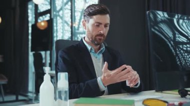 Genç adam, dizüstü bilgisayar karantinası, bilgisayar hijyenik ofis çalışanı, salgın hijyenik dezenfeksiyon pandemik yavaş çekim klavyesi üzerinde çalışmadan önce antiseptikle ellerini dezenfekte ediyor.